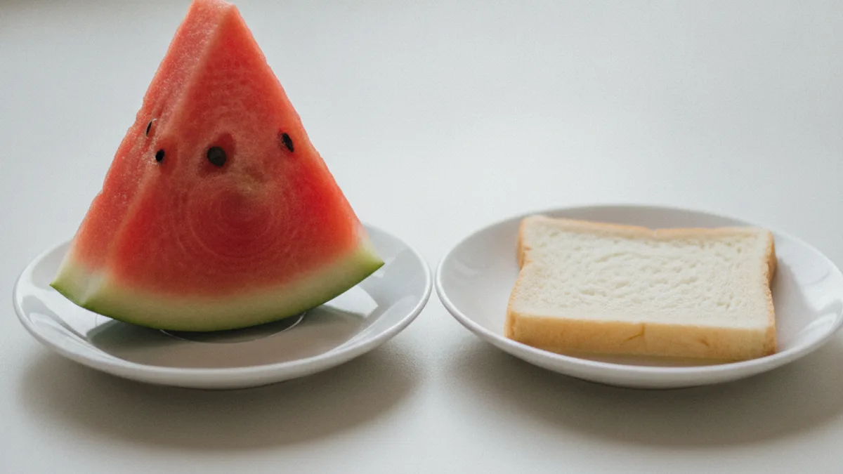 Two white saucers on a light-colored table: one holds a triangular slice of watermelon with seeds, the other holds a piece of white bread
